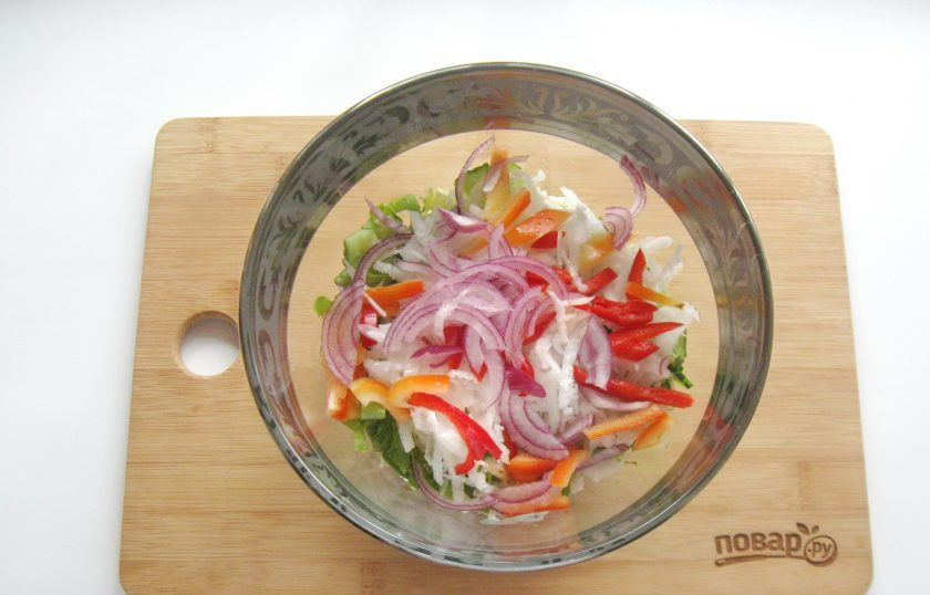 1. Этап. Постный салат из пекинской капусты: Красный лук очистите, помойте и нарежьте полукольцами. Выложите в салатник.
