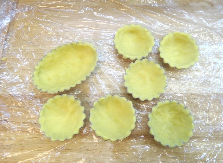 1. Этап. Тарталетки с фруктами в желе: Тесто достаньте из холодильника, разделите на части и распределите по формочкам. Формочки отправьте в холодильник еще на 15 минут.