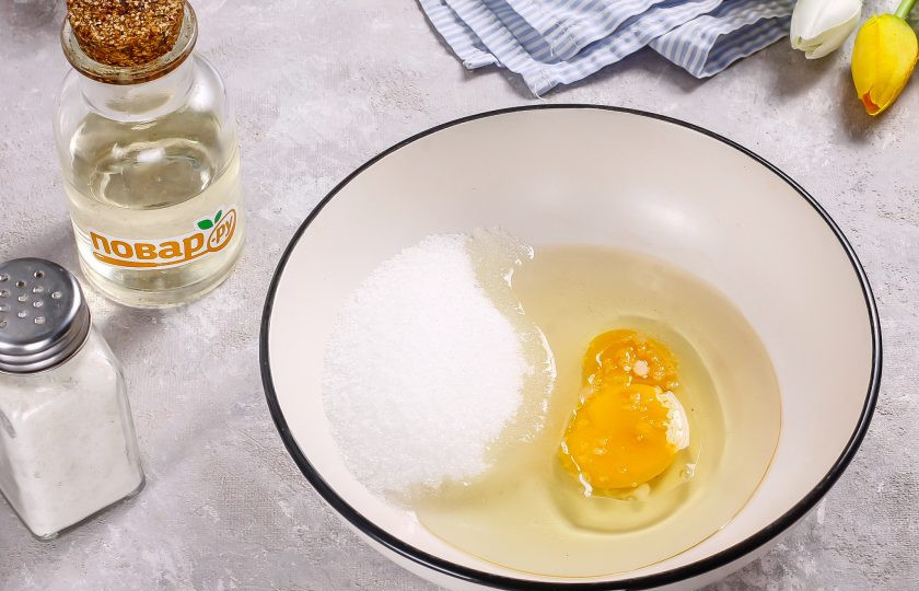 1. Этап. Творожное печенье с клюквой: В глубокой емкости взбейте сахар, куриное яйцо, соль и растительное масло. По желанию можете добавить немного ванильного сахара.