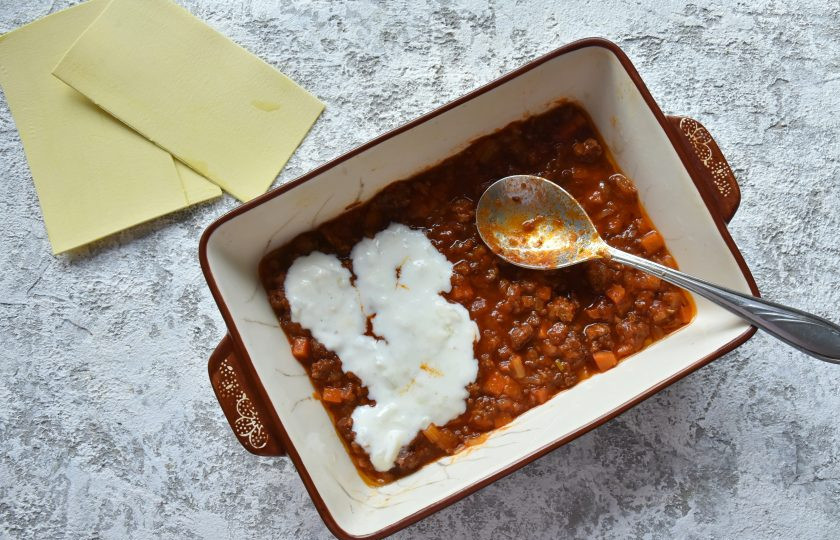 1. Этап. Лазанья с фаршем от Джейми Оливера: В форму выложите первым слоем рагу с фаршем. Слой не должен быть слишком толстым, достаточно 1 см. Поверх мясного соуса распределите белый соус.