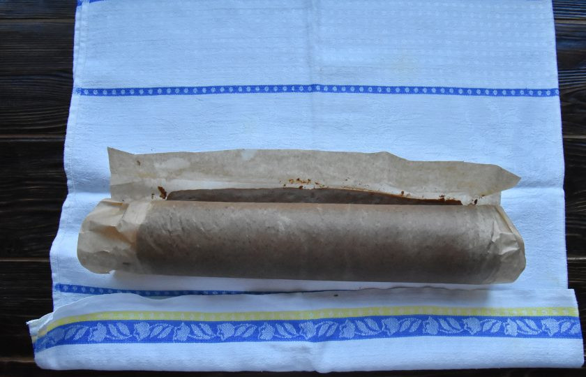 1. Этап. Торт Рождественское полено: Еще горячий бисквит вместе с пергаментом переложите на кухонное полотенце и сверните в рулет (вместе с пергаментом). Дайте время рулету полностью остыть.