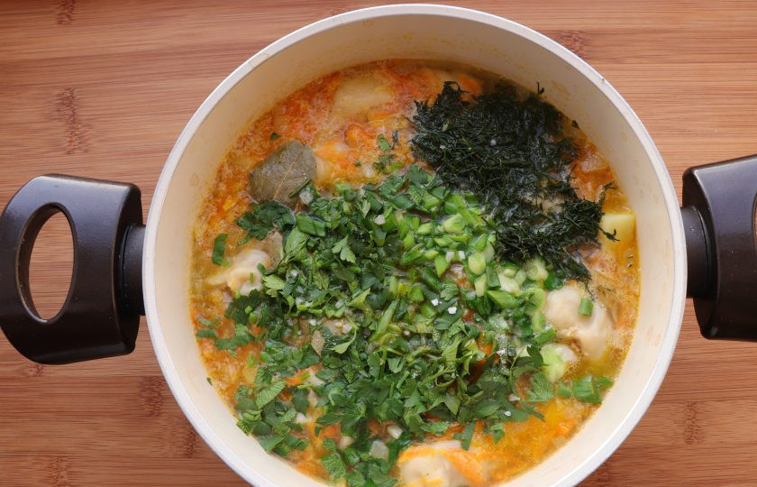 1. Этап. Суп с ленивыми пельменями: Добавьте лавровый лист, нарезанный зеленый лук и измельченную зелень. Готовьте еще 2 минуты. В конце посолите по вкусу.