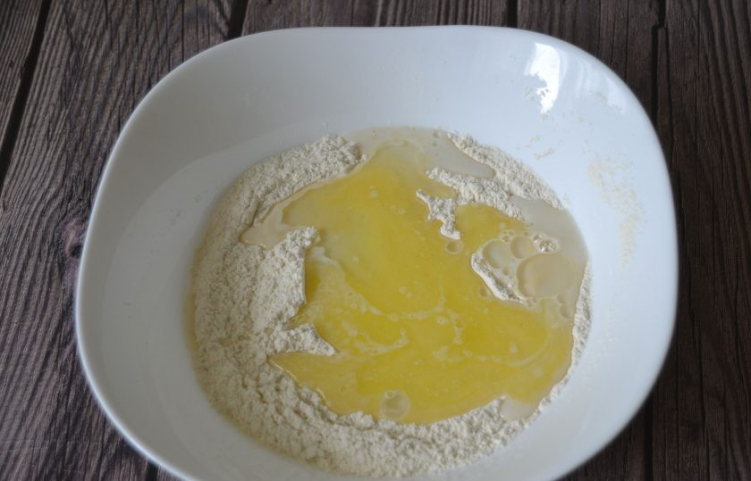 1. Этап. Воскресный пирог: Сделайте в муке углубление и влейте смесь молока с солью и сахаром, добавьте растительное масло и растопленное сливочное масло.