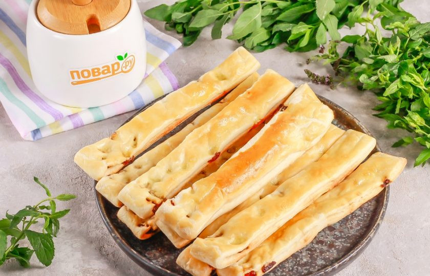 1. Этап. Слоеные палочки с изюмом и сахаром: Выложите нарезанные заготовки на противень или на пергаментную бумагу. Разогрейте духовку до 180 градусов и поместите в нее противень на верхний ярус. Выпекайте примерно 15 минут до румяности.