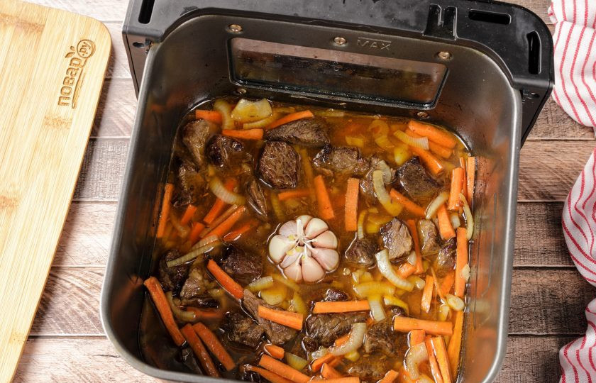 1. Этап. Плов в аэрогриле: Чеснок очистите от верхней шелухи, хорошо промойте и добавьте к мясу с овощами.