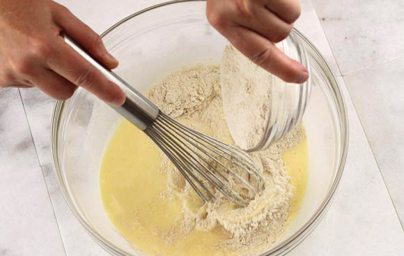 1. Этап. Блины с мёдом и орехами: Добавляем муку и орехи и тщательно перемешиваем до изчезновения комочков.