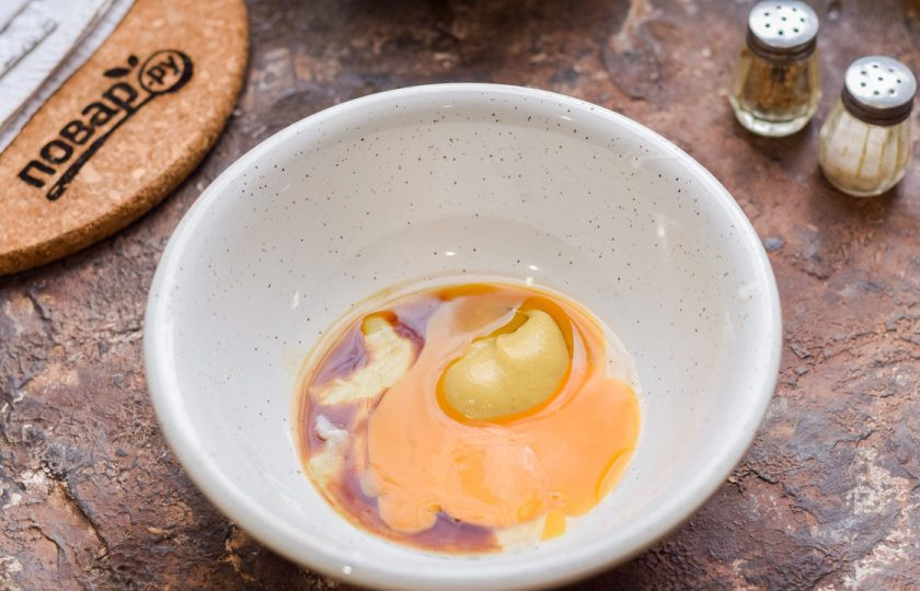 1. Этап. Салат Цезарь от Гордона Рамзи: В миску вбейте куриный желток, добавьте горчицу и соус.