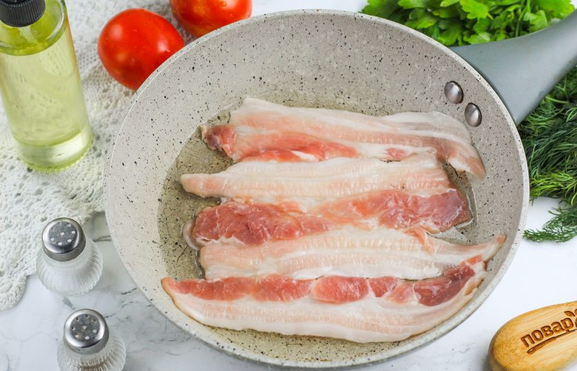 1. Этап. Булгур с беконом: Бекон промойте и просушите салфетками. Разделите пополам. Сбрызните сковороду растительным маслом и выложите на нее половину полосок бекона, обжарьте до румяности с обеих сторон.