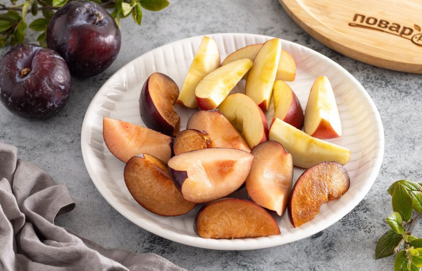 1. Этап. Компот из слив и яблок: Сливы помойте, разрежьте пополам и удалите косточки. Яблоки помойте, вырежьте сердцевину и порежьте на ломтики.