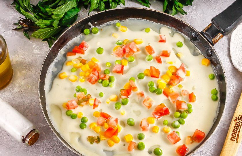 1. Этап. Мексиканские блины: В это время промойте и нарежьте помидор мелкими кубиками, удаляя сердцевинку. Прогрейте сковороду и смажьте ее первый раз растительным маслом. Влейте часть теста и быстро выложите в него кукурузу, горошек и нарезку помидора в хаотичном порядке. Если тесто уже 