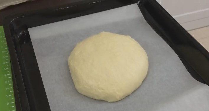 1. Этап. Очень вкусный домашний хлеб на кислом молоке: 8. Достаньте тесто, теперь его нужно еще раз обмять. Его консистенция должна поменяться, оно немножко может тянуться за руками, но муку больше не добавляйте. Сформируйте шар, выложите его на пергаментную бумагу. Накройте сверху полотенцем и дайте постоять еще 15 минут.