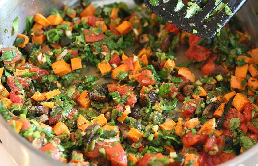 1. Этап. Вегетарианское тамале: 4. Приготовить начинку. Нарезать цуккини, зеленый лук и помидоры. Пропустить чеснок через пресс. Натереть сыр. Измельчить кинзу. Отжать сок из лайма. Обжарить цуккини, зеленый лук и чеснок в сковороде на среднем огне в 1 столовой ложке масла в течение 2-3 минут.