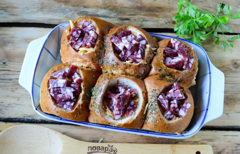 1. Этап. Булочки на завтрак: Сын натрите на крупной терке и положите по щепотке в каждую булочку. Колбасу порежьте на мелкие кусочки. Можно использовать также копченый бекон или другие мясные продукты, которые есть у вас в холодильнике. Положите колбасу сверху на сыр.