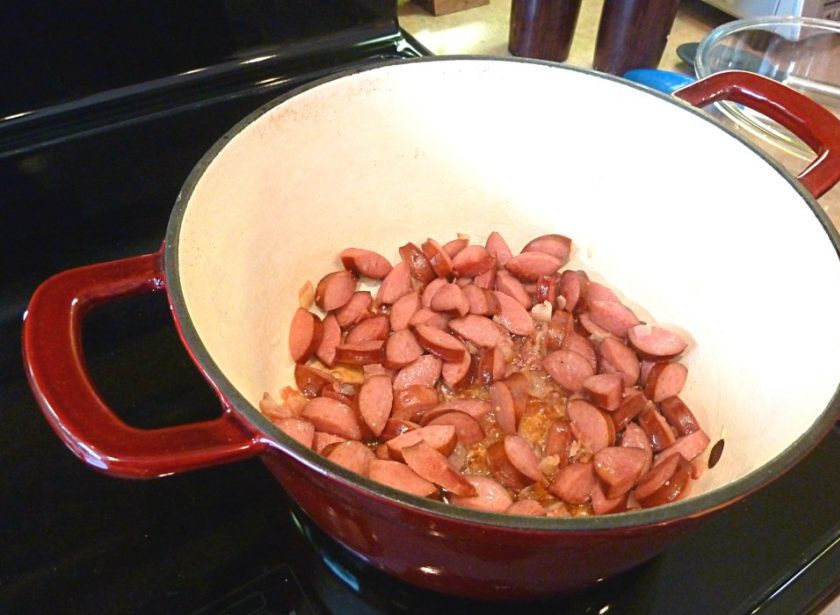 1. Этап. Жаркое по-польски: 2. Подготовьте жаропрочную кастрюлю. Обжарьте там нарезанный бекон до румяности. Снимите и выложите сосиски.