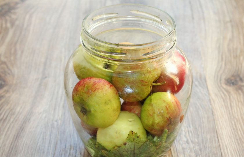 1. Этап. Моченые яблоки с брусникой: Выложите в банки чистые яблоки до горлышка.