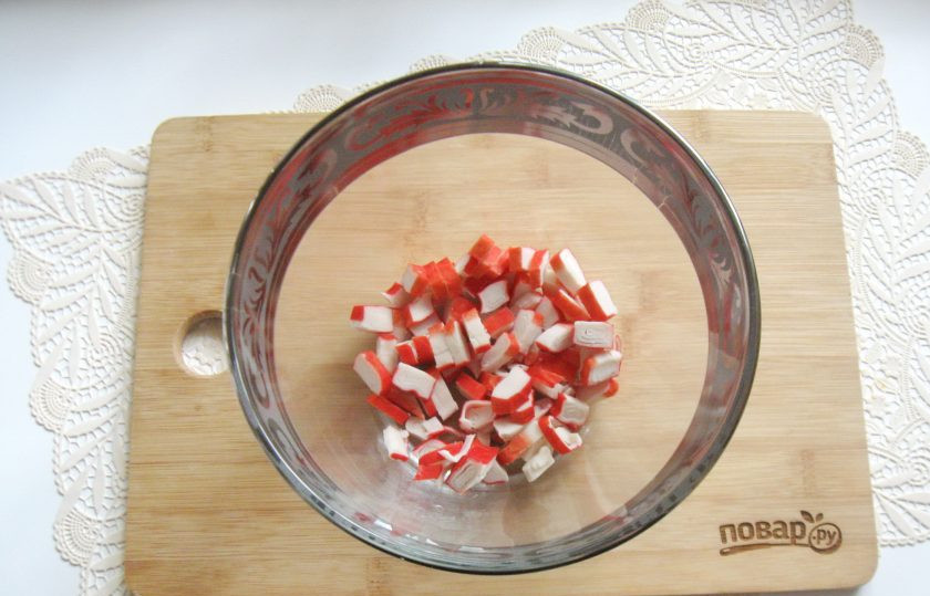 1. Этап. Зеленый салат с крабовыми палочками: Крабовые палочки мелко нарежьте и выложите в салатник.