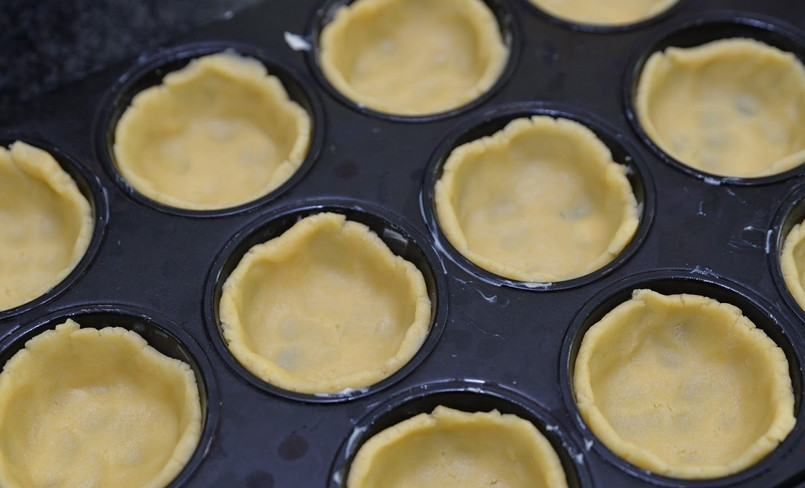 1. Этап. Тарталетки в духовке с начинкой: Выкладываем тесто в формы для запекания, формируя тарталетки. Ставим форму в морозилку на 30 минут.