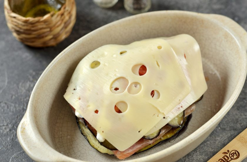 1. Этап. Форель с баклажанами в духовке: Накройте заготовку сверху тонкими ломтиками твердого сыра, который хорошо плавится в духовке. Отправьте форму в предварительно разогретую до 190 градусов духовку на 20 минут в режиме 