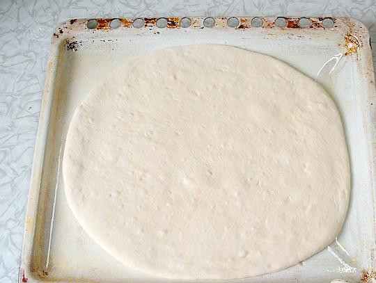 1. Этап. Пресный пирог с грибами: 4. Когда тесто подошло, разделяем его на две части (надо, чтобы одна часть была в два раза больше второй). На размер противня раскатываем в корж большую часть теста. Смазываем растительным маслом противень, и выкладываем на него корж. Аккуратно прижимаем корж к противню.