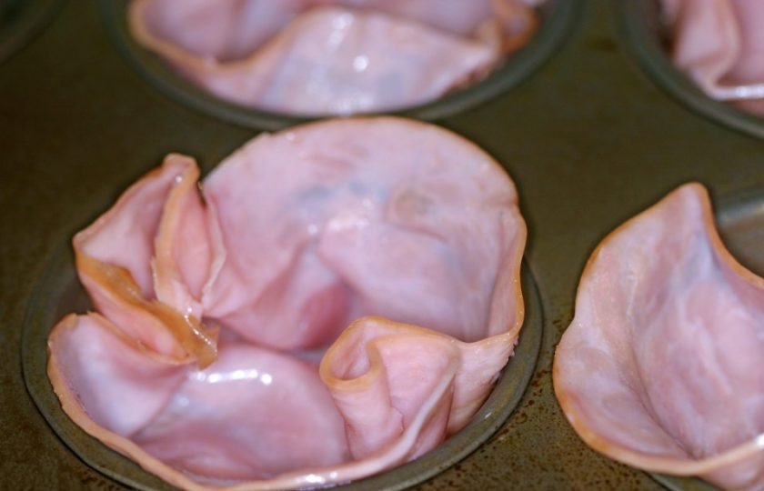 1. Этап. Ветчина на завтрак: 3. Смажьте формы для кексов растительным маслом. Нарежьте толстыми ломтиками колбасную ветчину и выложите по одному в каждую формочку, сформировав из каждой чашу.