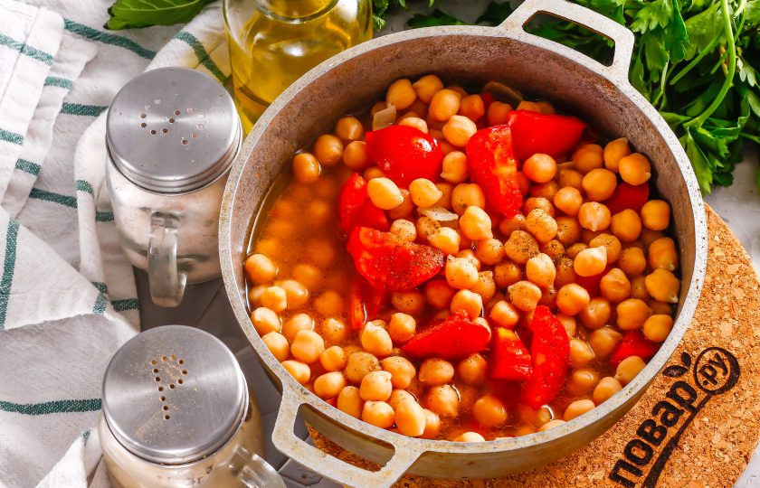 1. Этап. Тушеный нут с овощами: Помидоры промойте и вырежьте из плодов зеленые сердцевинки. Нарежьте средними кусочками и добавьте в емкость вместе с нутом.