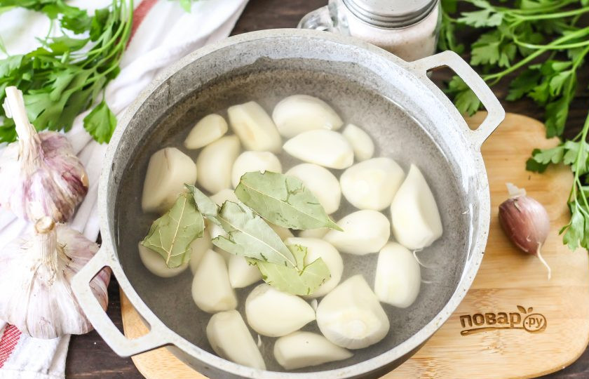 1. Этап. Чеснок маринованный по-грузински: Высыпьте зубчики в казан и залейте горячей водой. Добавьте лавровые листья и отварите примерно 1-2 минуты.
