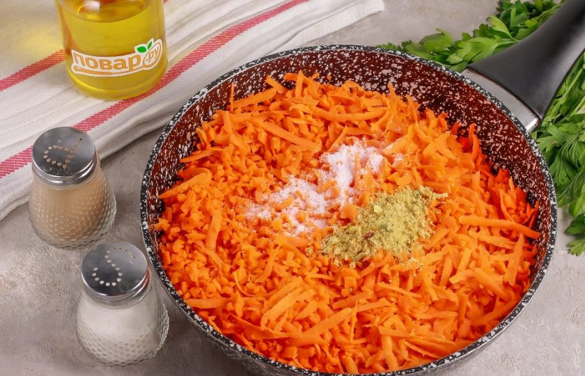 1. Этап. Икра из моркови с томатной пастой: Влейте в сковороду растительное масло, выложите натертую морковь и всыпьте все специи, приправы. Поместите емкость на плиту, включая умеренный нагрев.