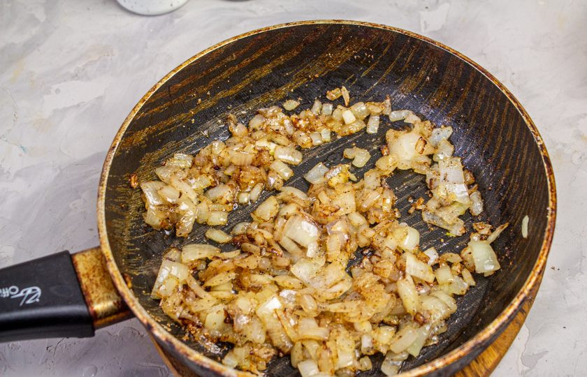 1. Этап. Салат Екатерина Мудрая: Лук мелко нарежьте и обжарьте на растительном масле до румяности. Дайте луку немного остыть.