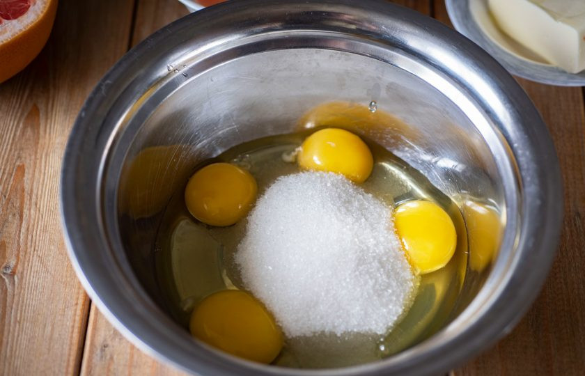 1. Этап. Грейпфрутовый курд: В просторную миску вбейте 2 яйца и добавьте еще 2 куриных желтка, отделив их аккуратно у двух других яиц. К яйцам добавьте сахар.