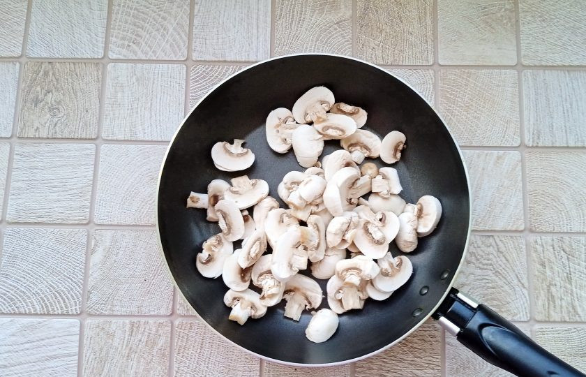 1. Этап. Слоёный салат с ананасами, курицей и жареными грибами: Грибы очистите, помойте и нарежьте пластинами. Выложите на сковороду и добавьте подсолнечное масло.