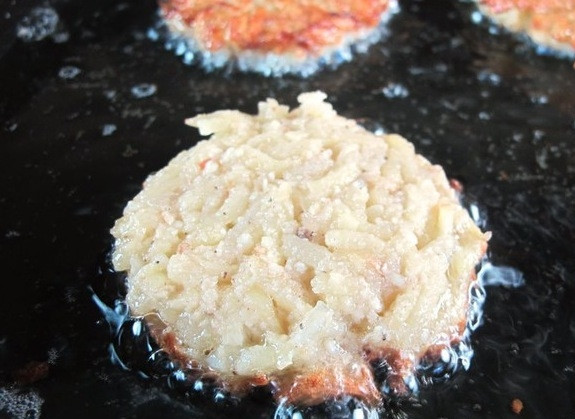 1. Этап. Латкес: Добавьте тертый лук, яйца и соль. Перемешайте. Из получившейся массы сформируйте лепешки и обжарьте их в большом количестве горячего масла до хрустящей корочки с каждой стороны.