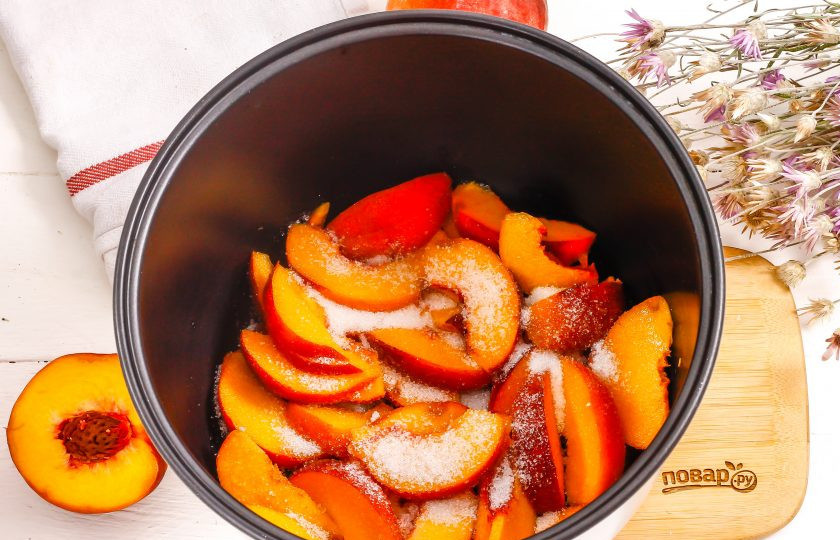 1. Этап. Варенье из персиков в мультиварке: Высыпьте персиковую нарезку в чашу мультиварки и добавьте туда же сахарный песок. Аккуратно перемешайте и активируйте технику на режим 