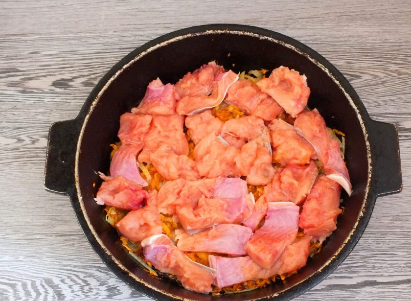 1. Этап. Плов из горбуши: Подготовленную горбушу выложите на обжаренные лук с морковью. Посолите, добавьте специи для рыбы.