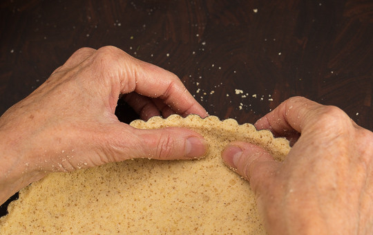 1. Этап. Грушевый пирог без глютена: 3. Подготовьте жаропрочную форму. Выложите крошку, сформируйте корж. Работать с таким тестом одно удовольствие, оно податливое и прекрасно лепится. Теперь нужно отправить форму в духовку минут на 12-15, чтобы корж немного подрумянился. Можно накрыть тесто листом пергамента, а сверху насыпать фасоль или горох, чтобы корж в процессе выпечки не поднимался.