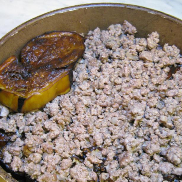 1. Этап. Имам: В сковороду с высокими краями, выложите нижний слой из жаренных баклажан, затем слой фарша и заключительный слой баклажан.