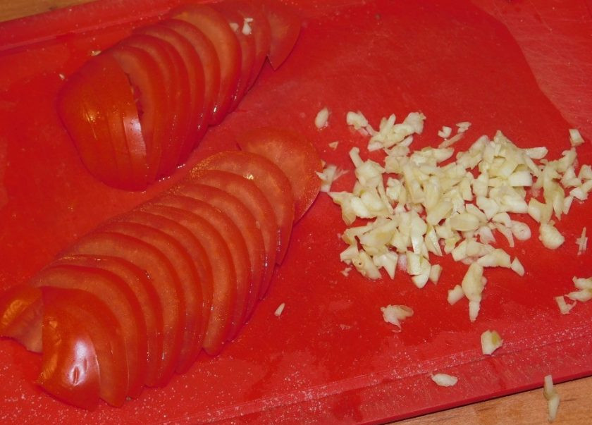 1. Этап. Фаршированная свинина из духовки: Нарежьте помидоры и измельчите чеснок.
