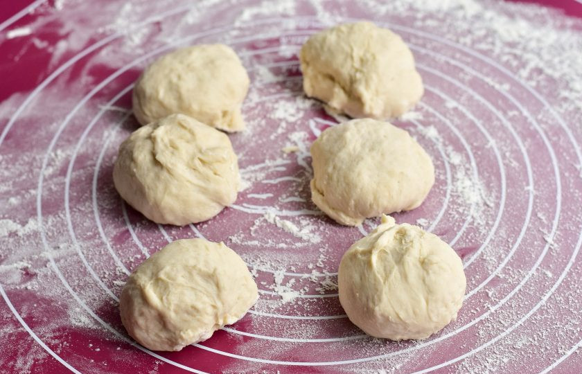 1. Этап. Булочки Бао: Обомните поднявшееся тесто, выложите его на силиконовый коврик и поделите на равные кусочки.