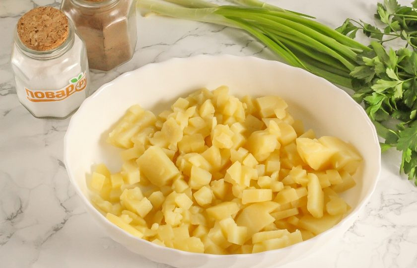 1. Этап. Салат Русские традиции с красной рыбой: Очистите отварной картофель от кожуры и нарежьте его мелкими кубиками. Высыпьте нарезку в салатник.
