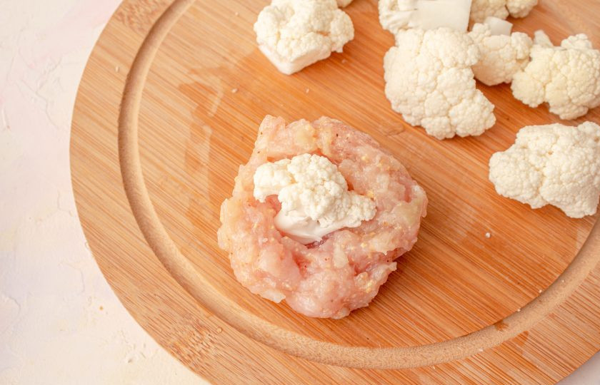 1. Этап. Мясные колобки с хрустящей корочкой и цветной капустой: Слегка влажными руками возьмите немного фарша, сформируйте лепешку, в середину вставьте 1 соцветие капусты.