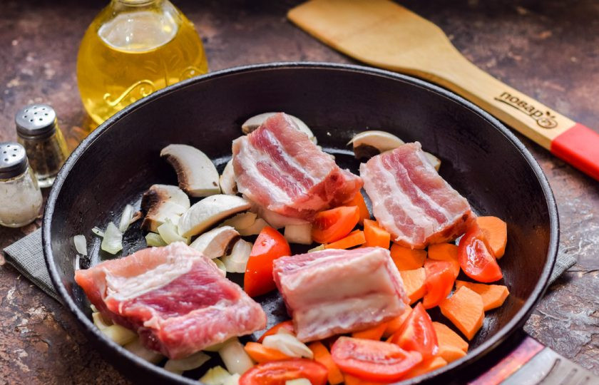 1. Этап. Ребрышки с перловкой: Сковороду прогрейте и влейте масло. Выложите овощи и нарезанные порционно ребра.