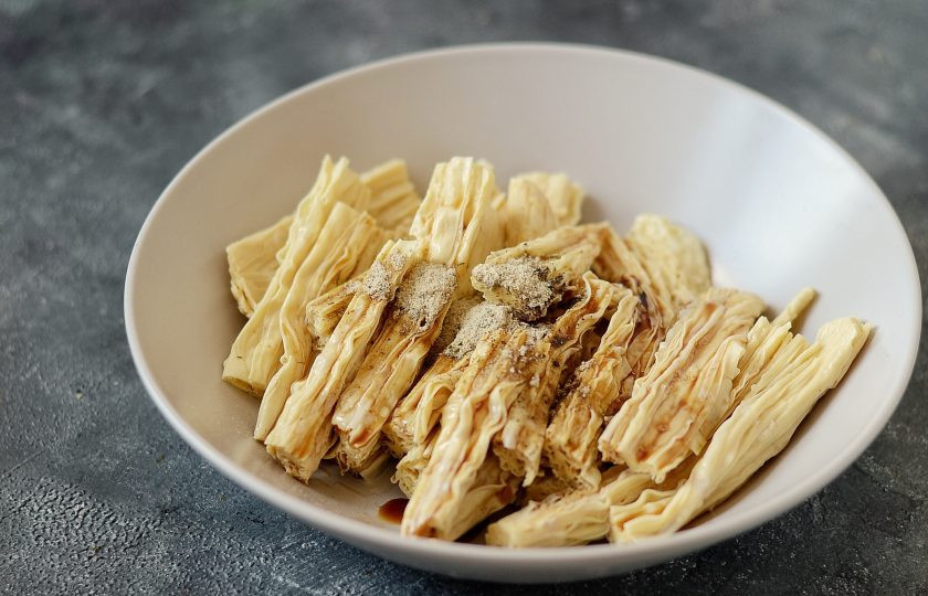 1. Этап. Жареная соевая спаржа: Промойте соевую спаржу, отожмите от излишков воды. Разрежьте на ломтики по 7-9 см. длиной. Переложите в контейнер, добавьте кунжутное масло, соевый соус, щепотку перца и приправу для рыбы. Хорошенько перемешайте, чтобы специи равномерно распределились по спарже. Уберите в холодильник на пару часов, чтобы закуска промариновалась.