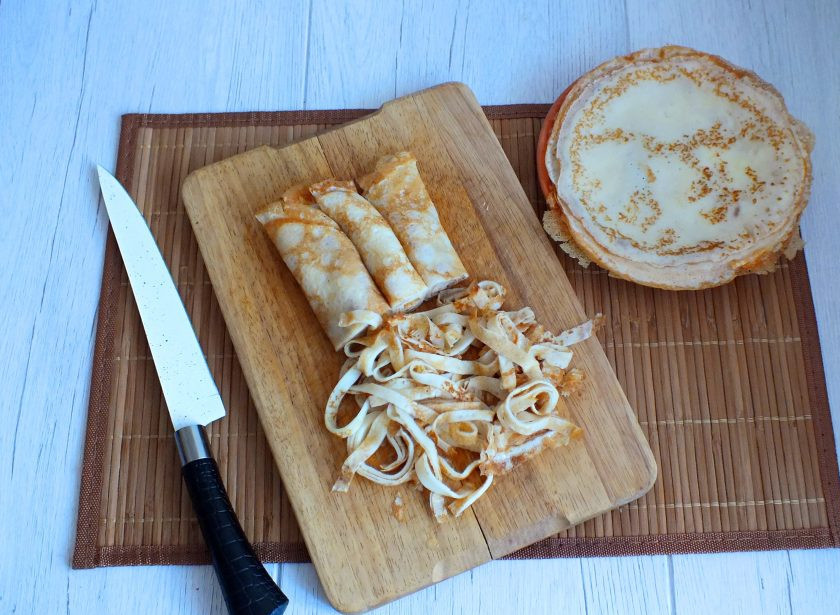 1. Этап. Лапшевник из блинов: Блинчики скрутите трубочкой и нарежьте тонкой лапшой.