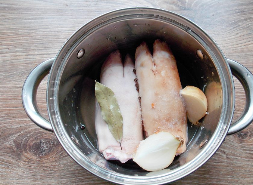 1. Этап. Свиные ножки с капустой: Свиные ножки опалите, если нужно и тщательно почистите, а затем промойте. Выложите в кастрюлю, добавьте одну разрезанную луковицу, лавровый лист, черный перец. Залейте все водой и посолите.