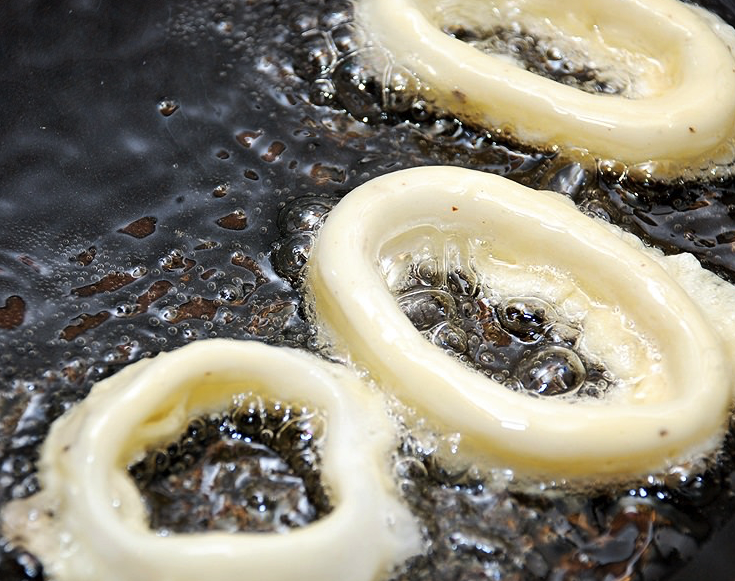 1. Этап. Кальмары в масле: Чтобы кляр получился нужной консистенции, то есть довольно густым, можете добавить в него больше муки. Аккуратно окунайте в кляр каждое кольцо, а затем выкладывайте на сковороду. Удобнее всего делать это при помощи вилки. Перед жаркой сковороду надо хорошо раскалить и налить туда растительное масло так, чтобы кольца были полностью в него погружены. Жарьте кальмары до аппетитной золотистой корочки.