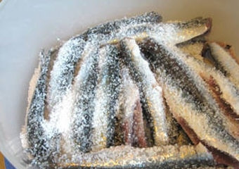 1. Этап. Засолка хамсы: 3. Удалив голову и внутренности, выложите рыбку в глубокую мисочку и залейте водой. Через полчаса воду замените чистой. Этот процесс повторите 3-4 раза. После с помощью бумажной салфетки обсушите немного и выложите в мисочку, засыпав 3-4 ложками соли.