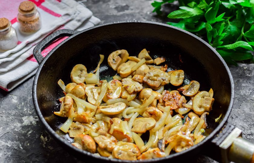 1. Этап. Салат Кальмаровый пир: В сковороде разогрейте масло, выложите лук и грибы, жарьте 5-7 минут.
