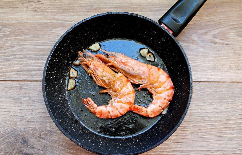 1. Этап. Салат с авокадо и лангустинами: В сковороду налейте одну столовую ложку растительного масла и разогрейте на среднем огне. Чеснок почистите и порежьте пластинками, выложите в масло. Обжаривайте чеснок в течение 30 секунд на среднем огне. Выложите лангустины и обжаривайте их с двух сторон, пока они не покраснеют. На это уйдет примерно 2-3 минуты с каждой стороны. Снимите их со сковороды и дайте остыть.