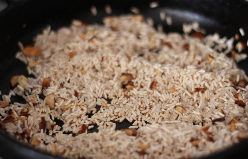 1. Этап. Рис с зеленым горошком и миндалем: Рис добавить в сковородку и жарить его около двух минут на несильно огне.