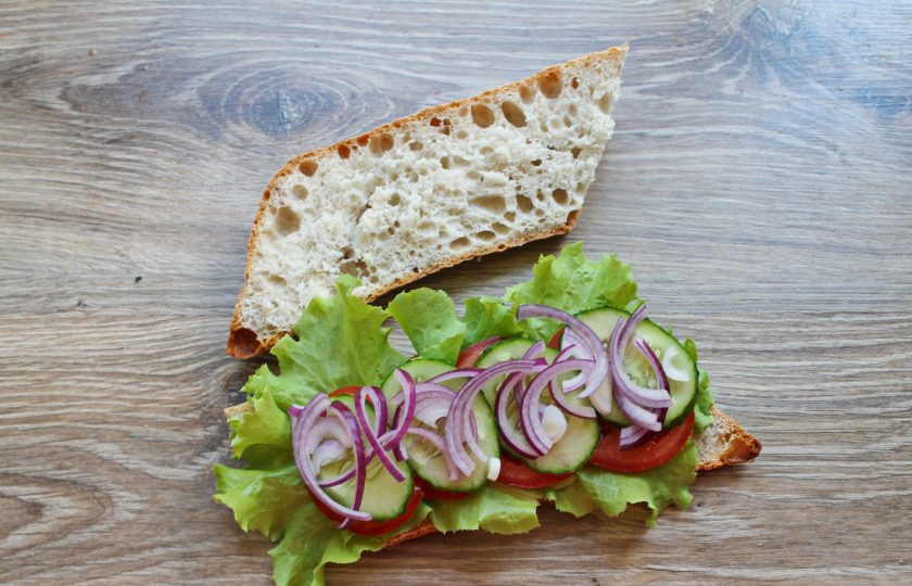 1. Этап. Греческий сэндвич: Почистите красный лук и порежьте полукольцами. Равномерно разложите его на огуречный слой.