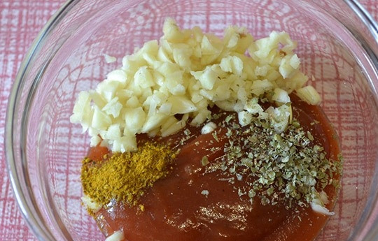 1. Этап. Куриные ножки, запеченные в мультиварке: 4. В небольшой емкости смешайте томатную пасту, измельченные зубчики чеснока, соль, карри, майоран и любые специи по вкусу.